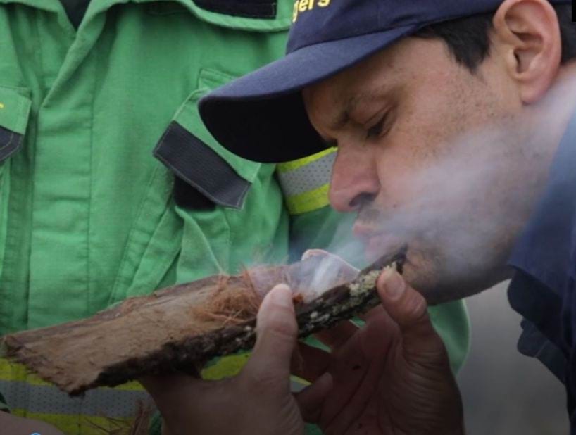 Kurtonitj cultural burn Indigenous Man blowing smoke from a broken off tree bark