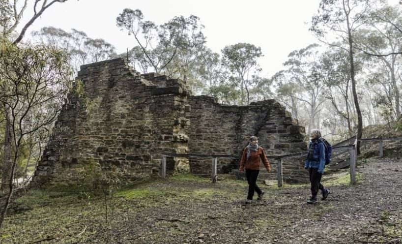 Women walking in countryside in front of ruins 