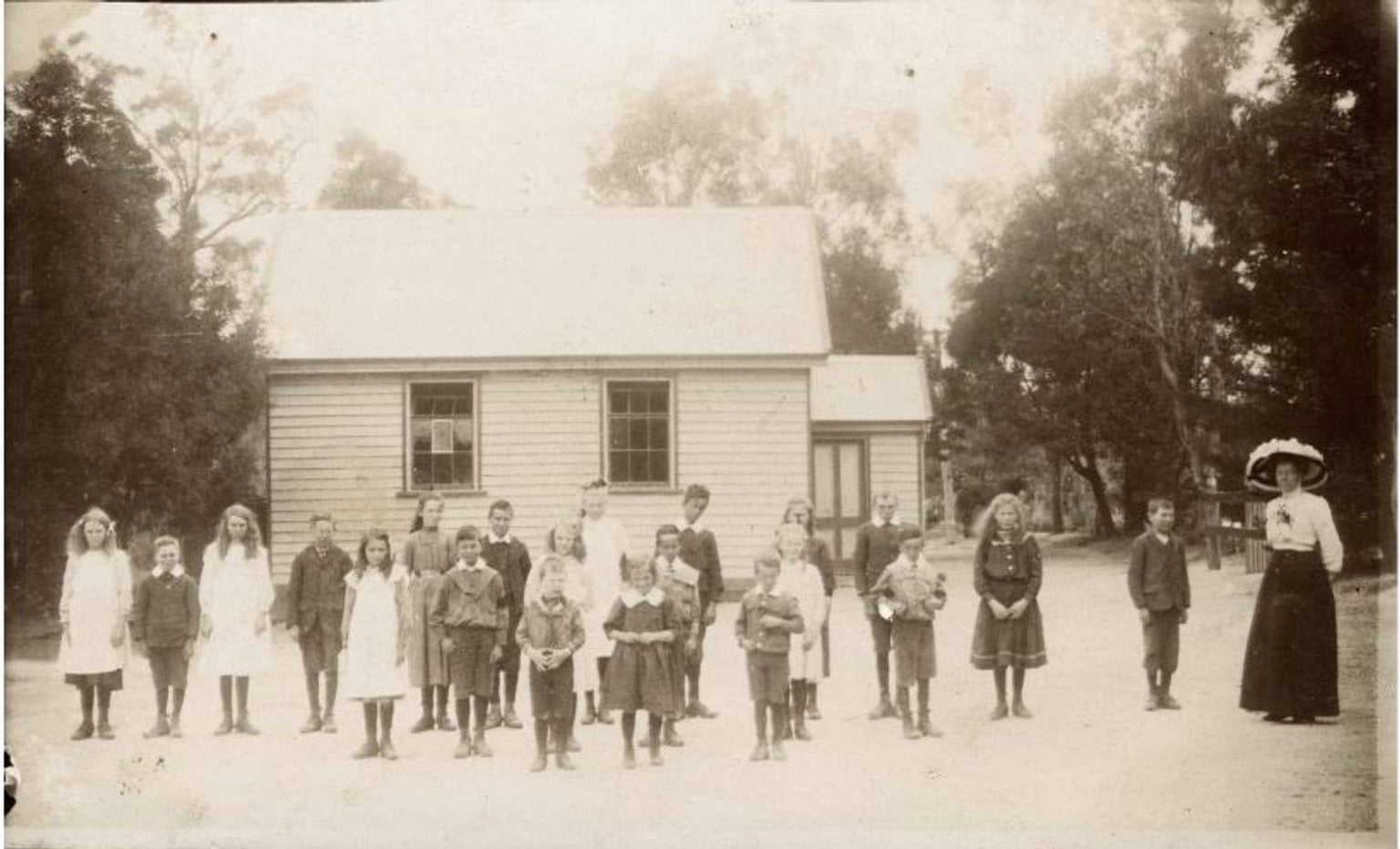 School children and teacher outside small timber Yeodene Primary School in 1911