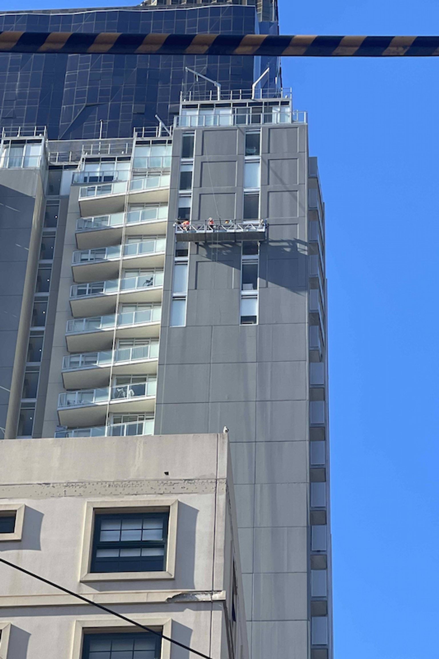 People working on a platform on the side of a high-rise building. 