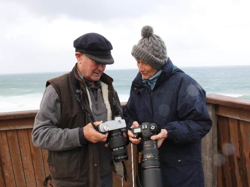 Two people holding cameras with both looking at the screen of one