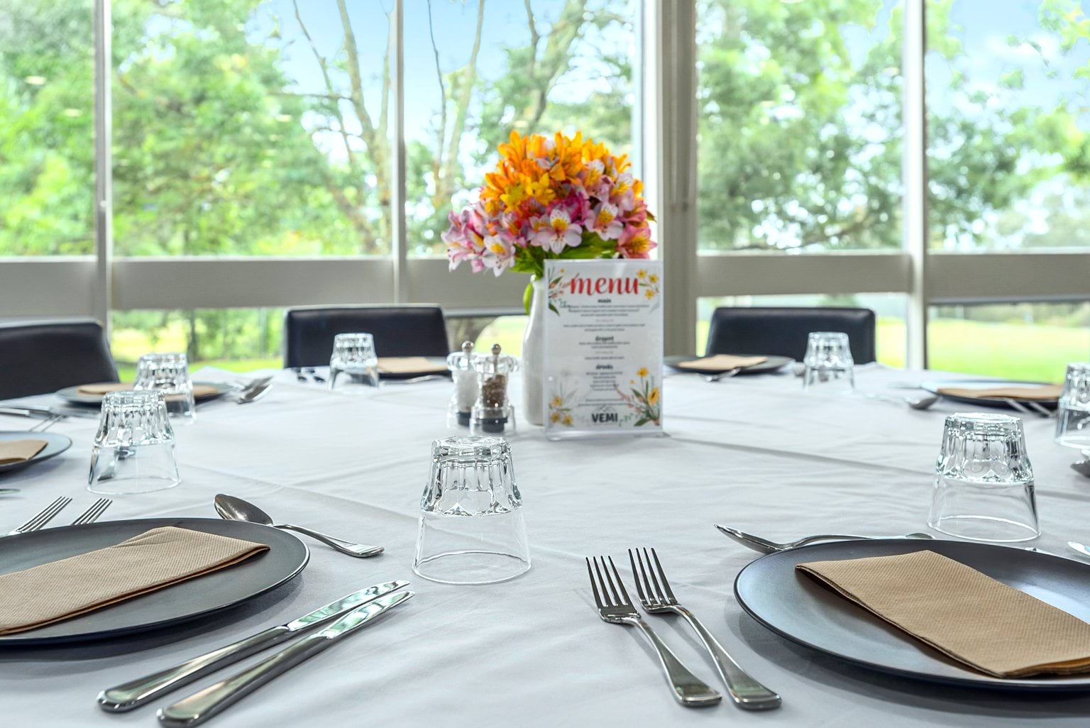 Image shows a table set with plates and cutlery on a white tablecloth and flowers at the centre.
