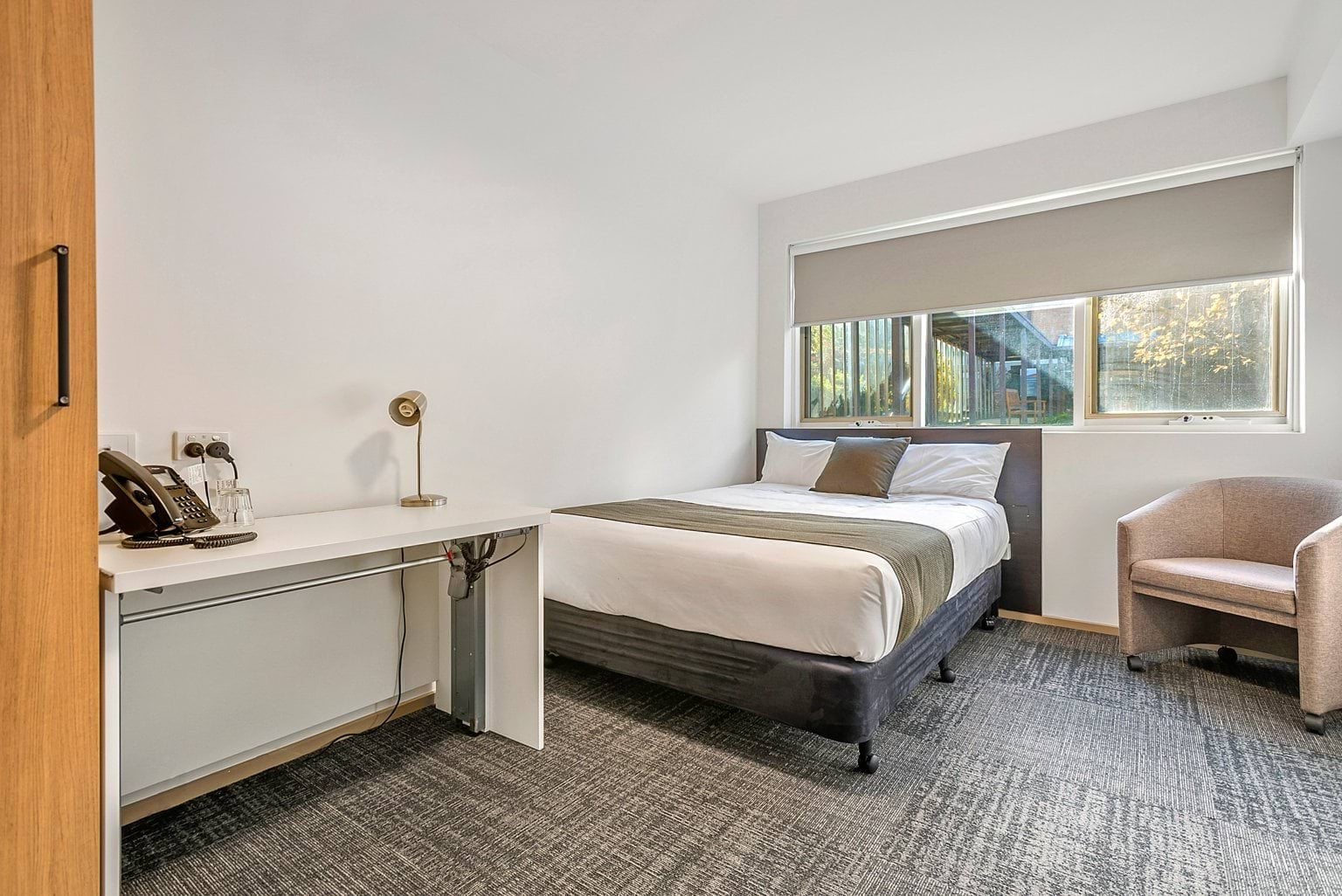Image shows the VEMI accommodation. A bed, desk, chair, wardrobe and chair in a room