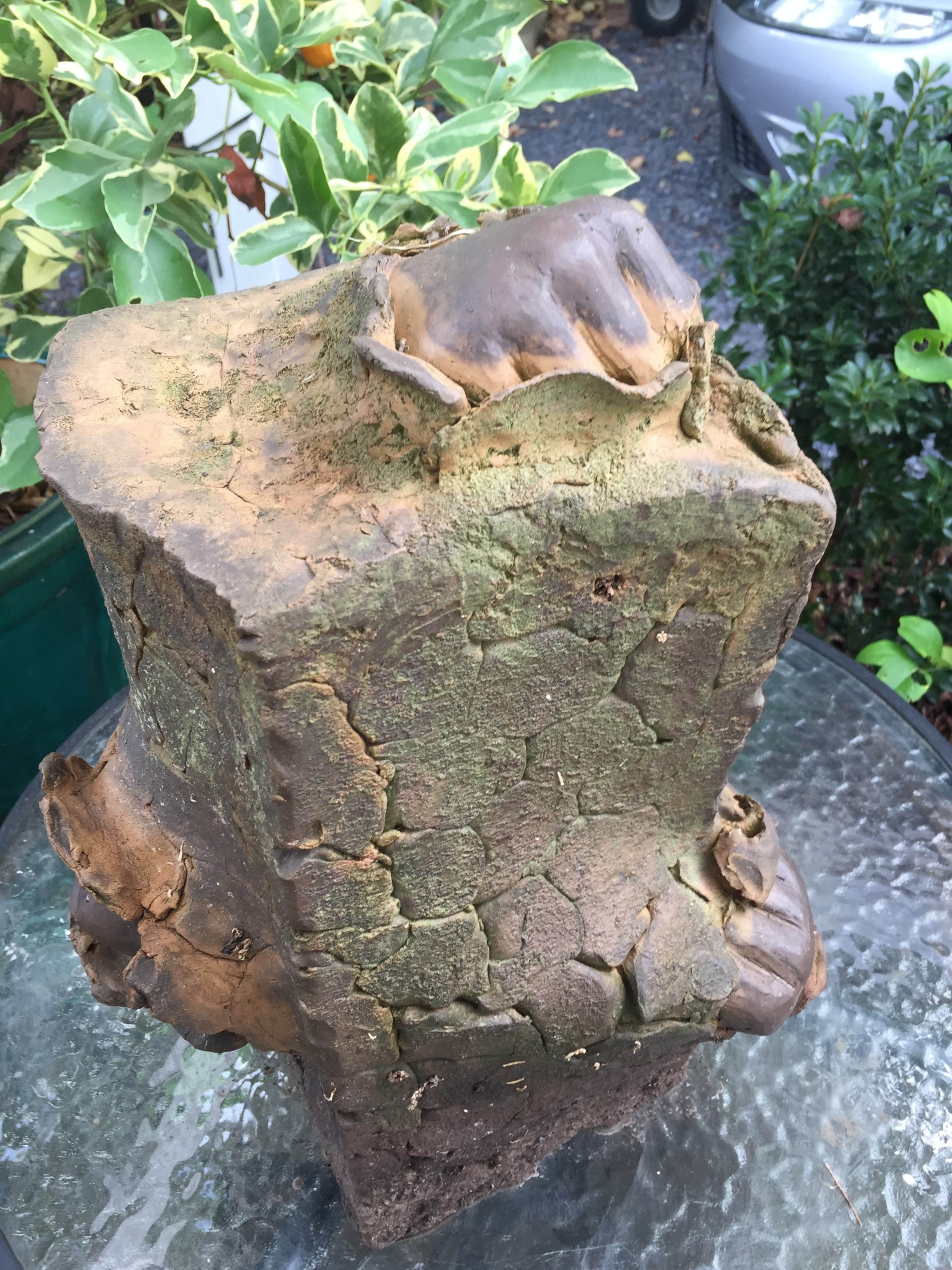 A pottery piece depicting a brick with three fists punching through the brick. 