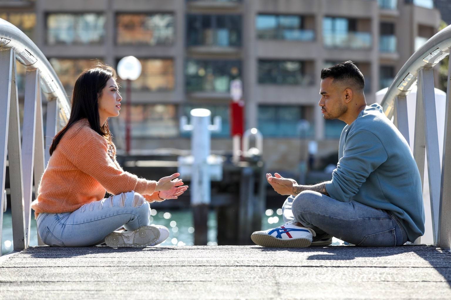 A woman and man sit cross legged facing each other talking 