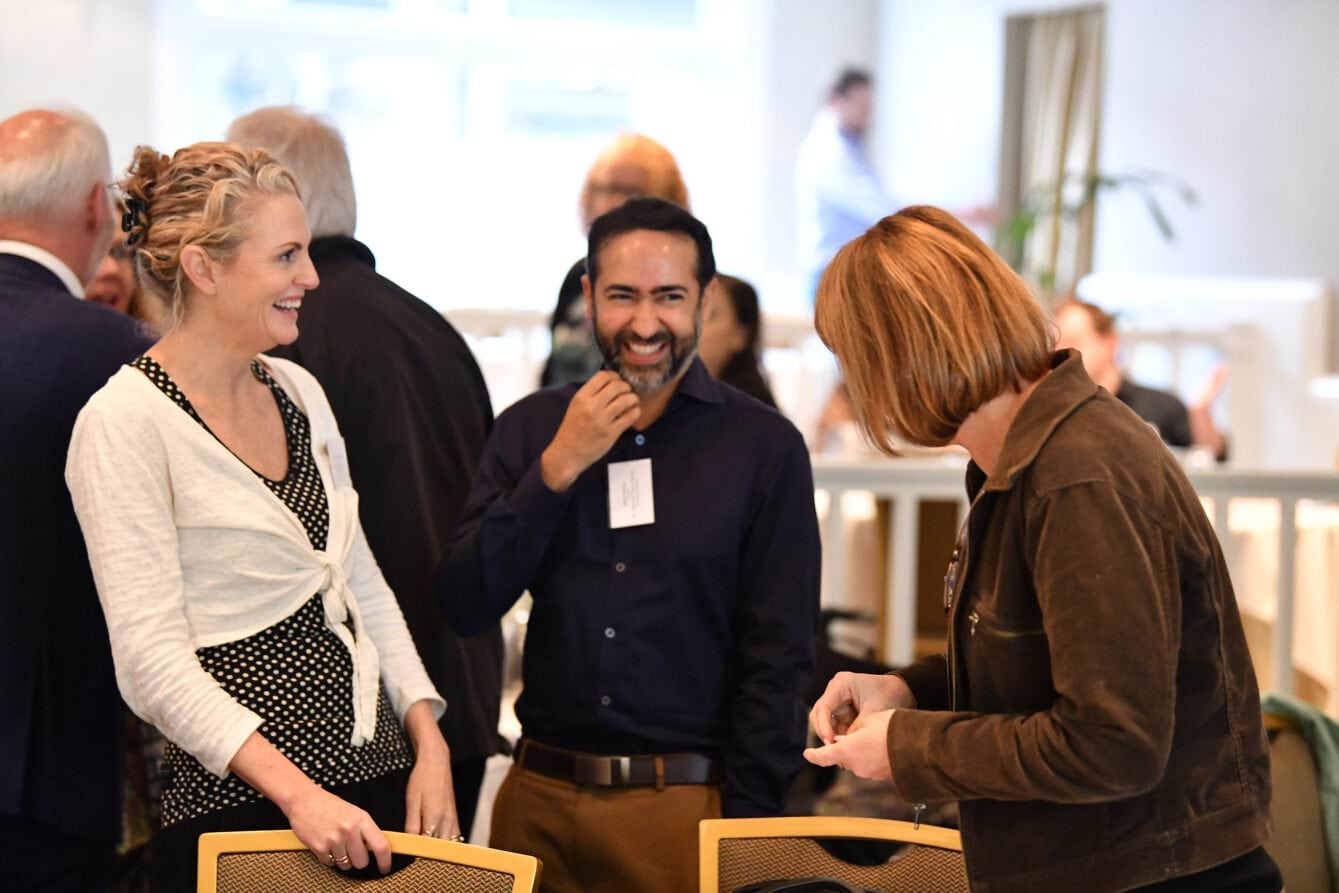 Image of three attendees laughing and smiling at the Collaborative Centre forum in April 2023