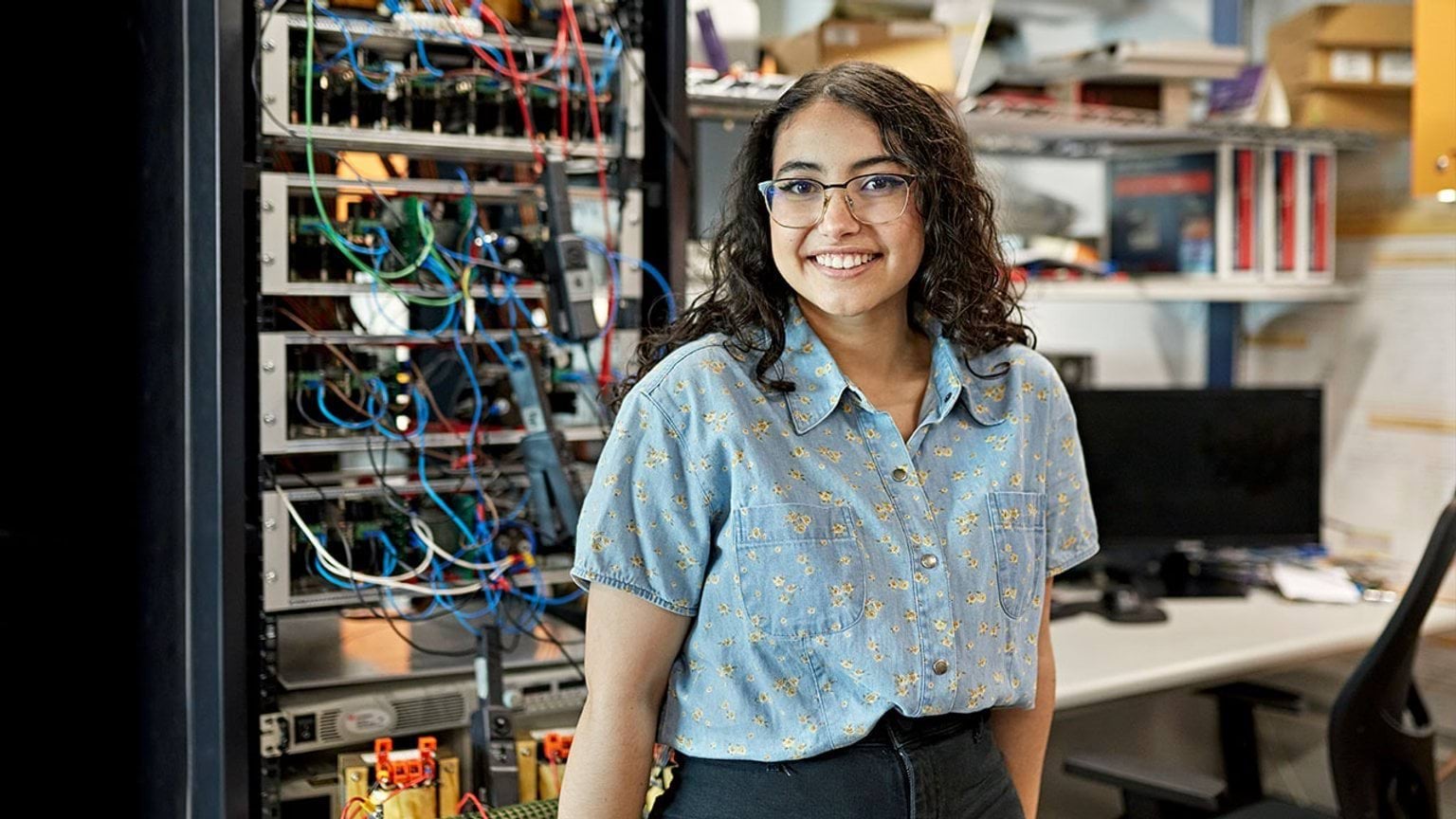 Person standing in front of computer networking cabinet