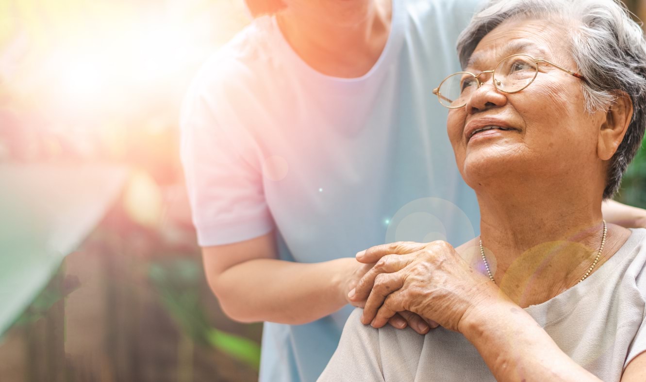 An older person is holding hands with a carer