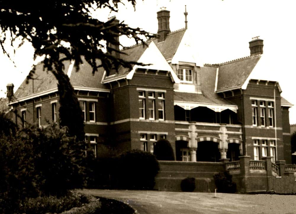 Sepia toned photo of the Caloola Sunbury brick building with three storeys and large windows.