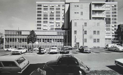 Sepia toned photo of the view from Cardigan Street of the 3AW Community Service Building, Carlton taken in 1972. The building is a glass and concrete structure, with a carpark out front.
