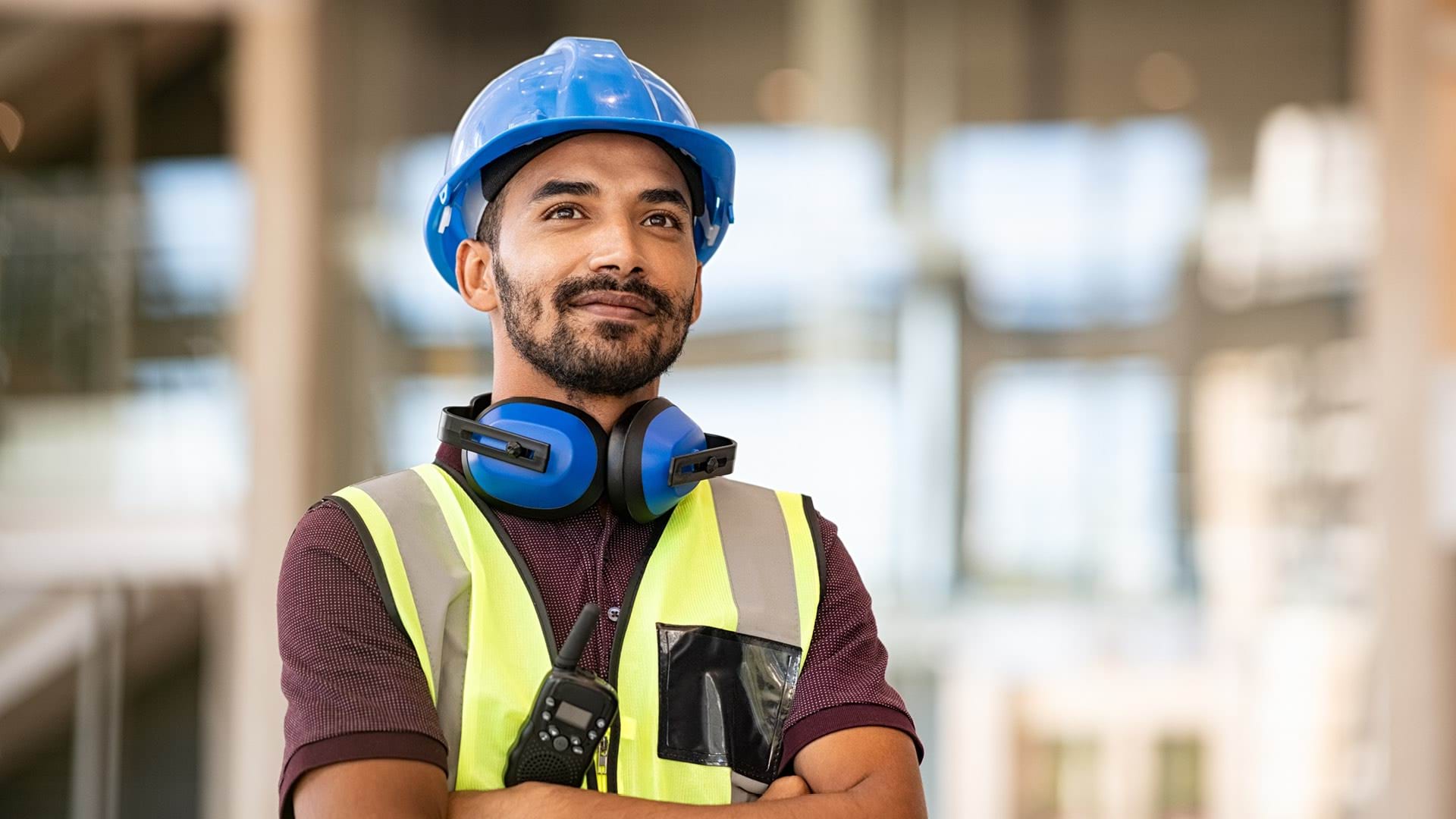 construction worker standing with arms crossed and in blue hard hat