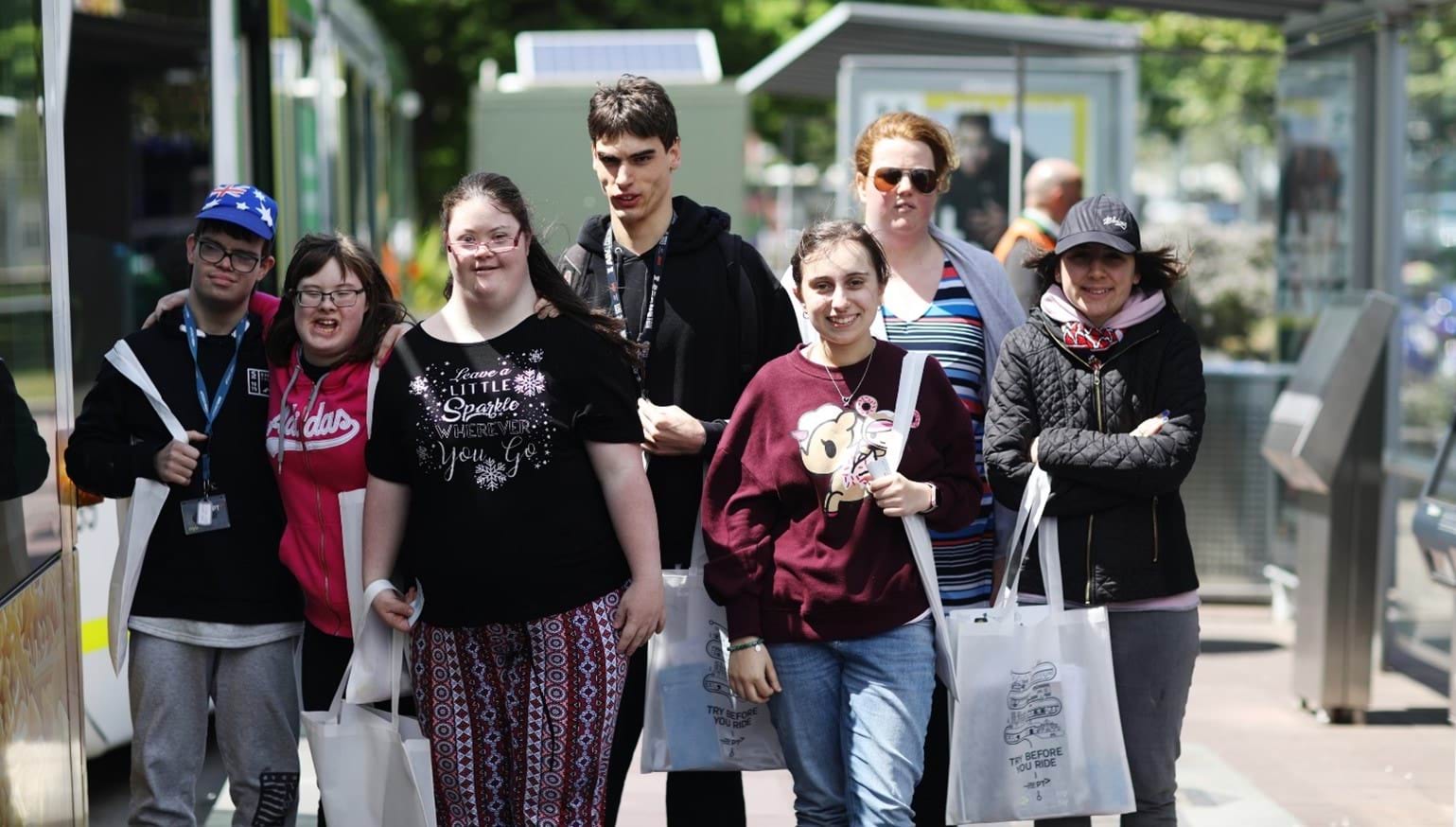 A group of people walking walking a level access tram stop.