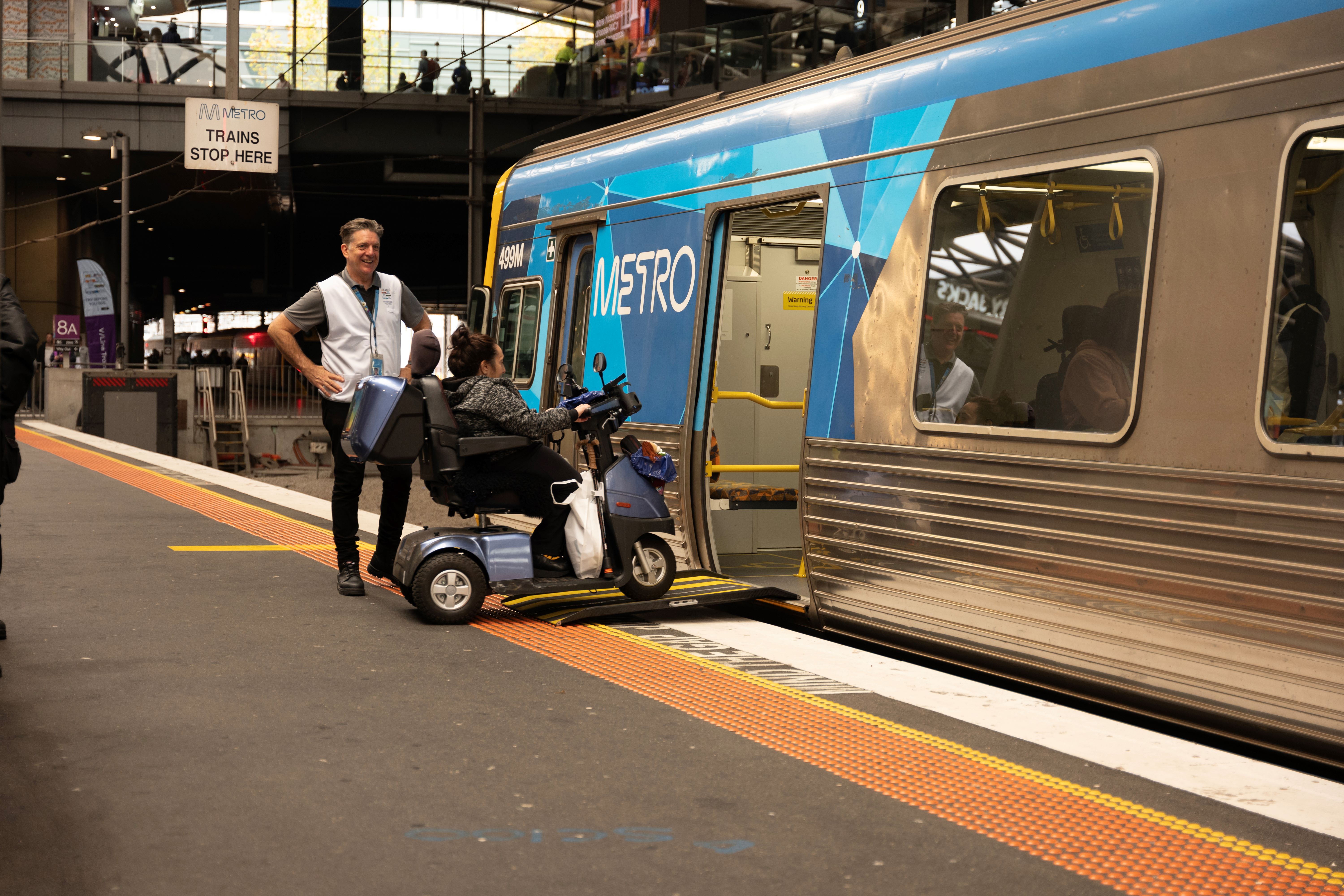 A person using a mobility scooter boarding via a ramp at the first door of a metropolitan train carriage at Southern Cross Station as part of Try Before You Ride.