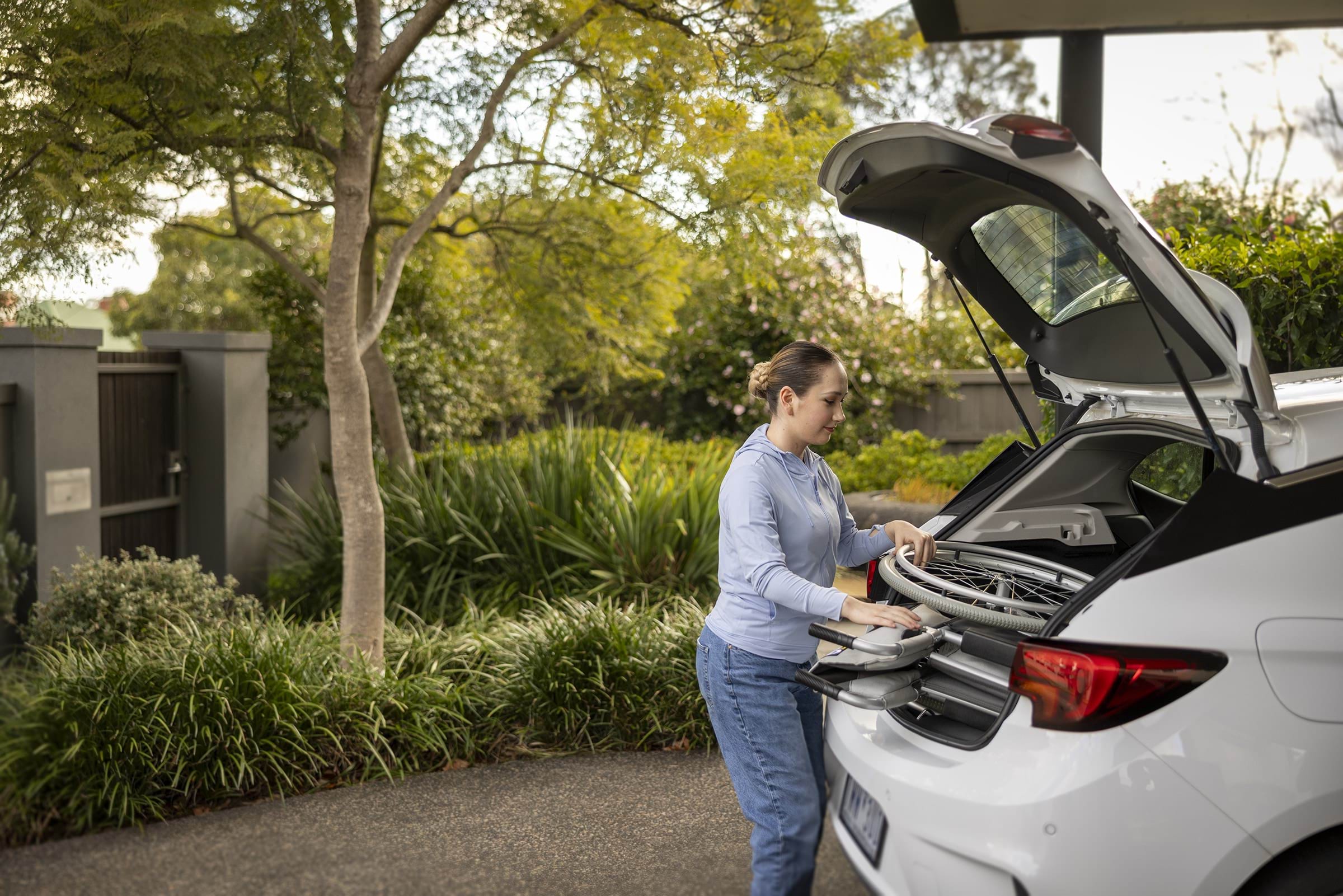 Image of a person putting a wheelchair into a car boot.