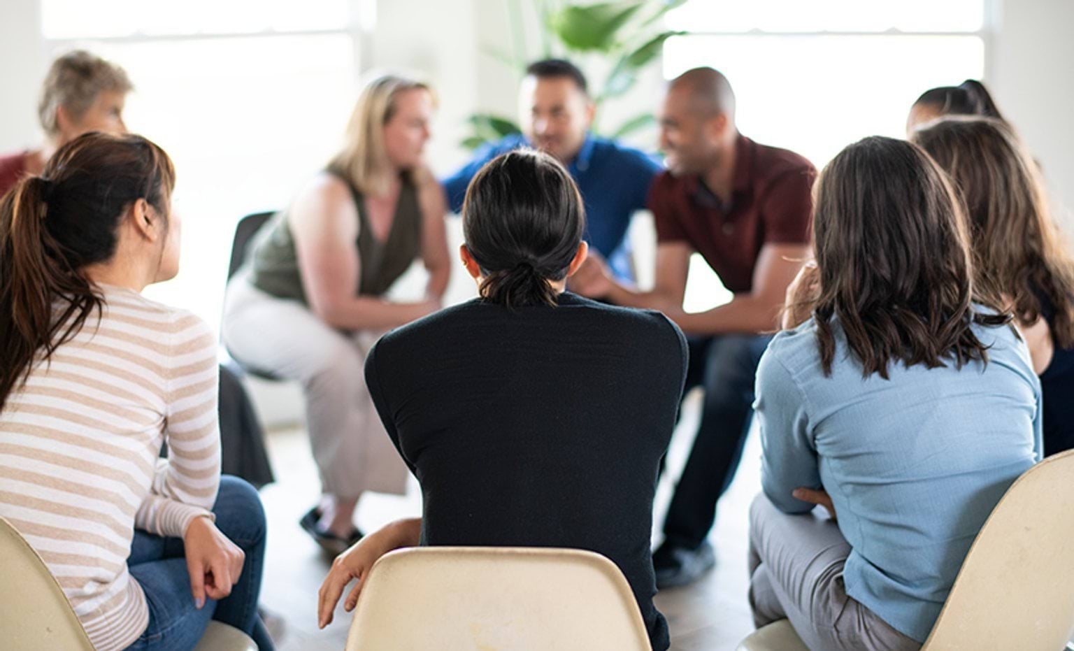 A group of people talking, sitting in a circle on chairs