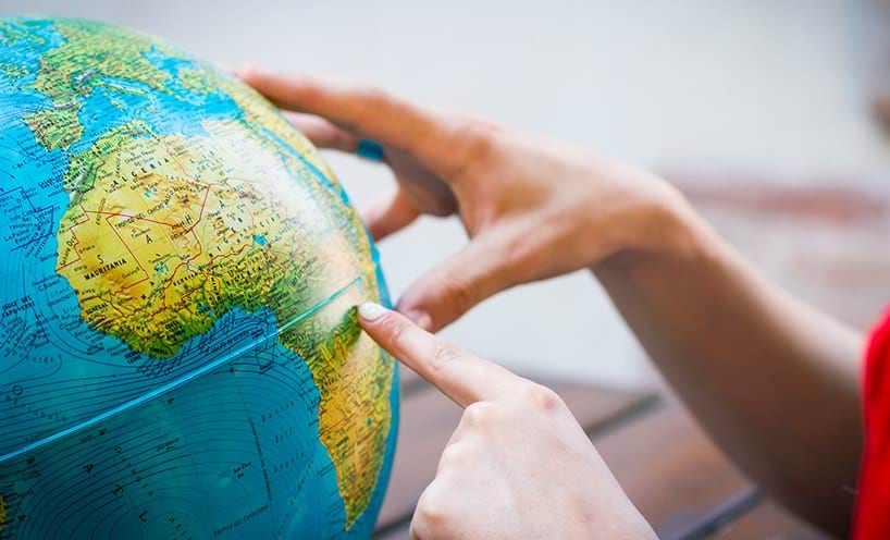Two hands exploring the globe