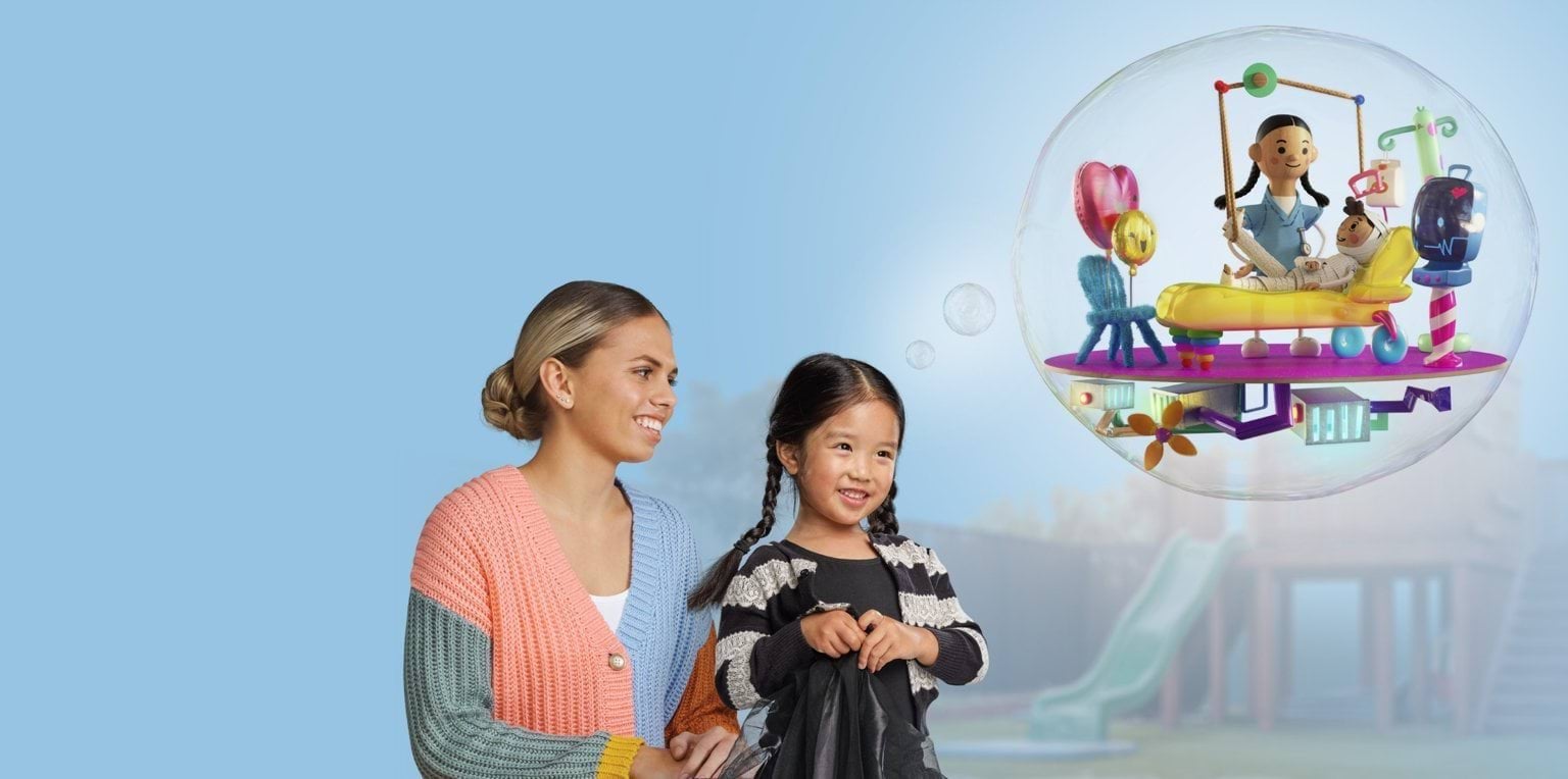 A smiling woman and a young child stand together in front of a playground. The child points excitedly to a thought bubble above them, showing a playful cartoon scene of a nurse in a hospital, caring for a young patient. The background is a soft blue.