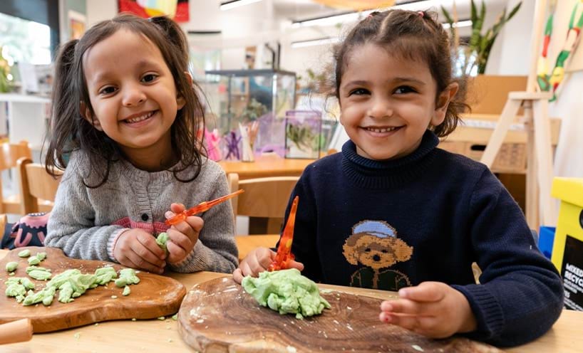 Two children smiling and playing with playdough
