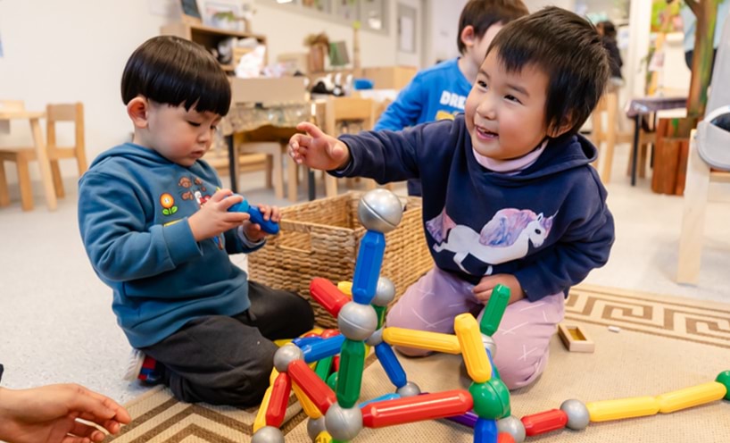 Two children playing with magnetic building sticks