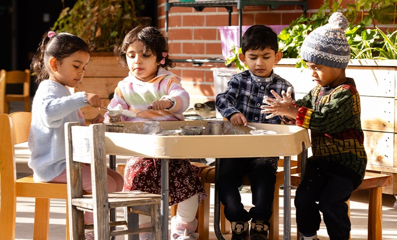 Children engaged in an experience around a sensory table