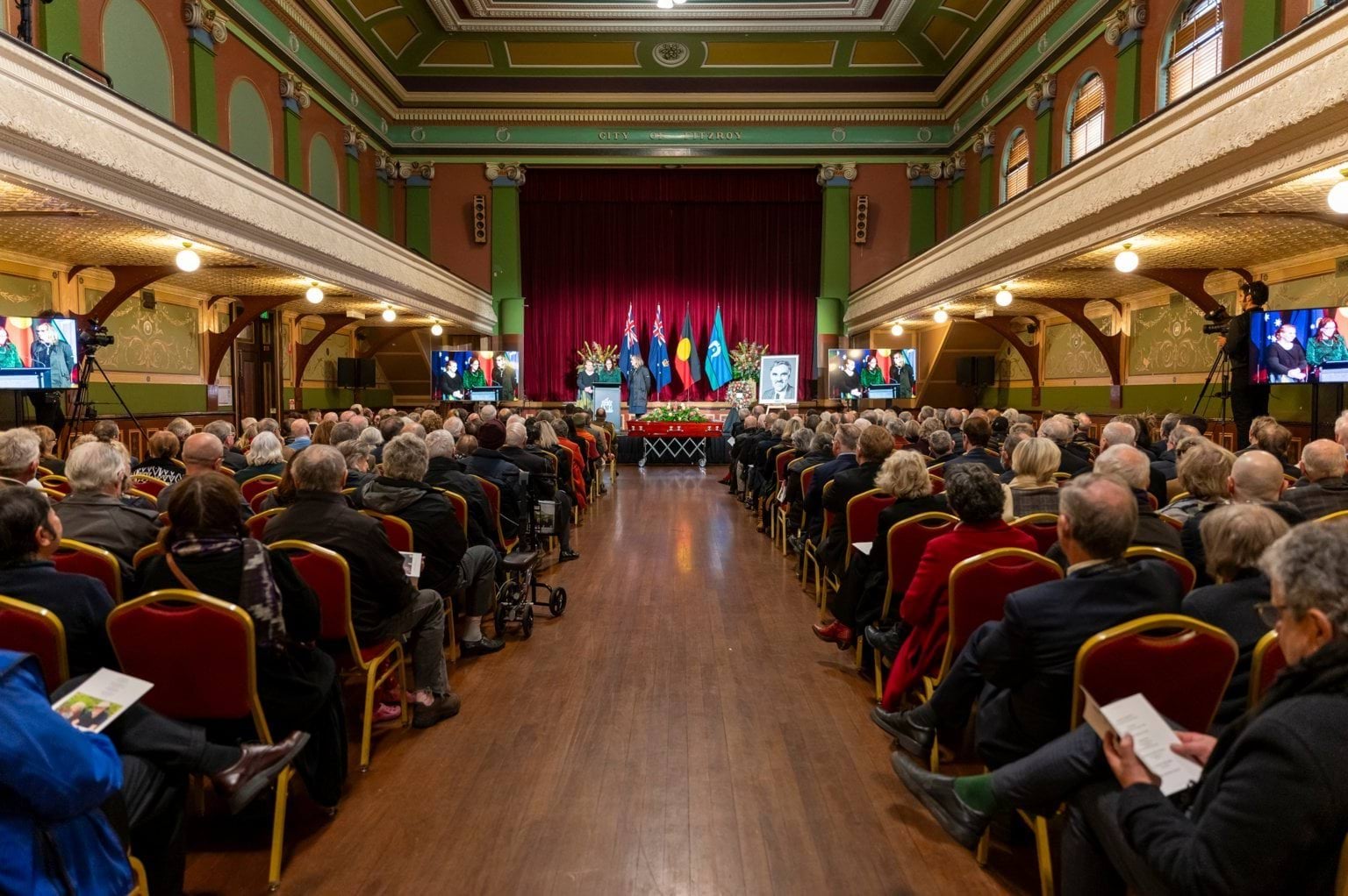 Guests seated in Fitzroy Town Hall at the State Funeral Service for The Honourable Barry Pullen