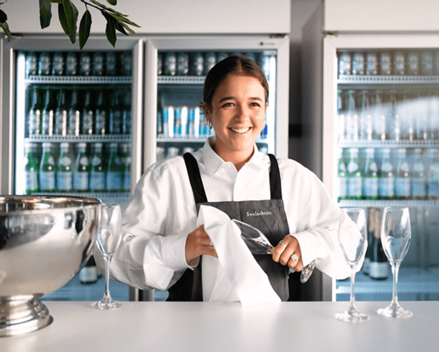 Bar worker polishing a wine glass in hospitality setting