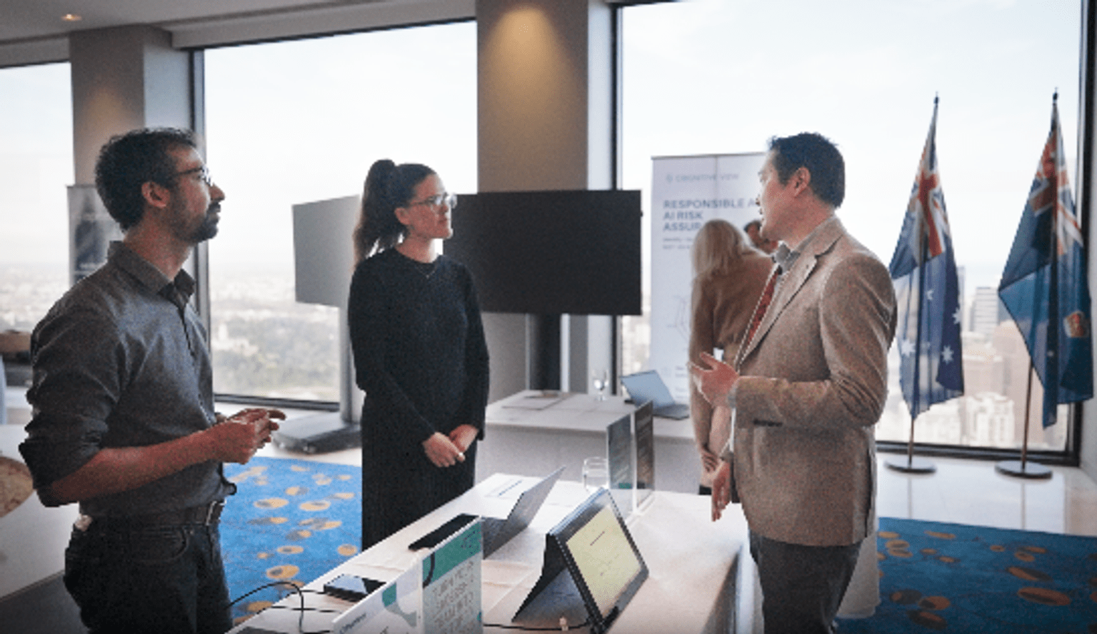 Three people stand in a room at the AI Roadshow event