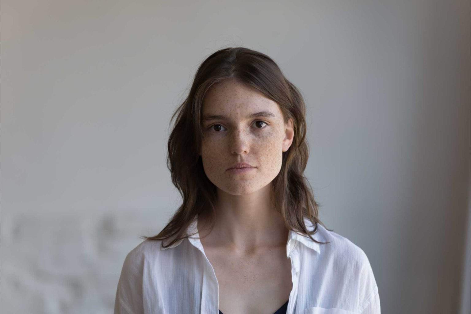 A woman looks directly into the camera with a neutral expression