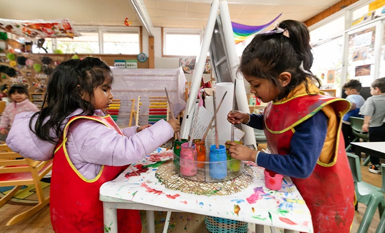 Two children painting on a canvas each