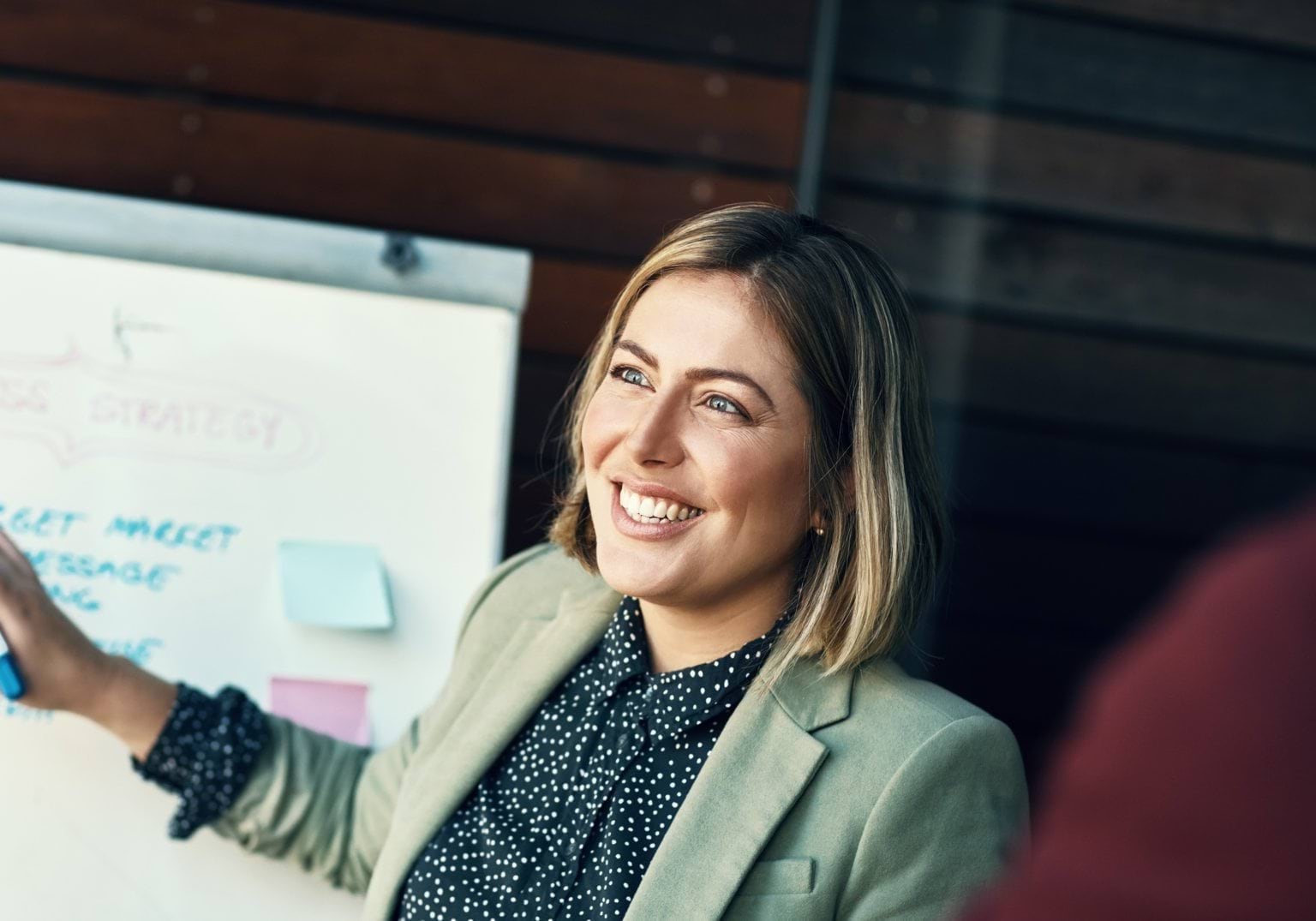 Woman smiling while pointing at a whiteboard 