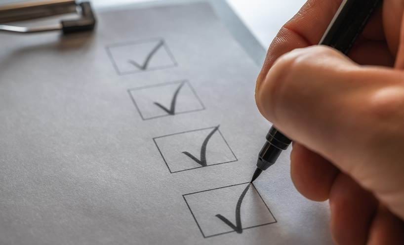 A checklist on a clipboard being ticked off