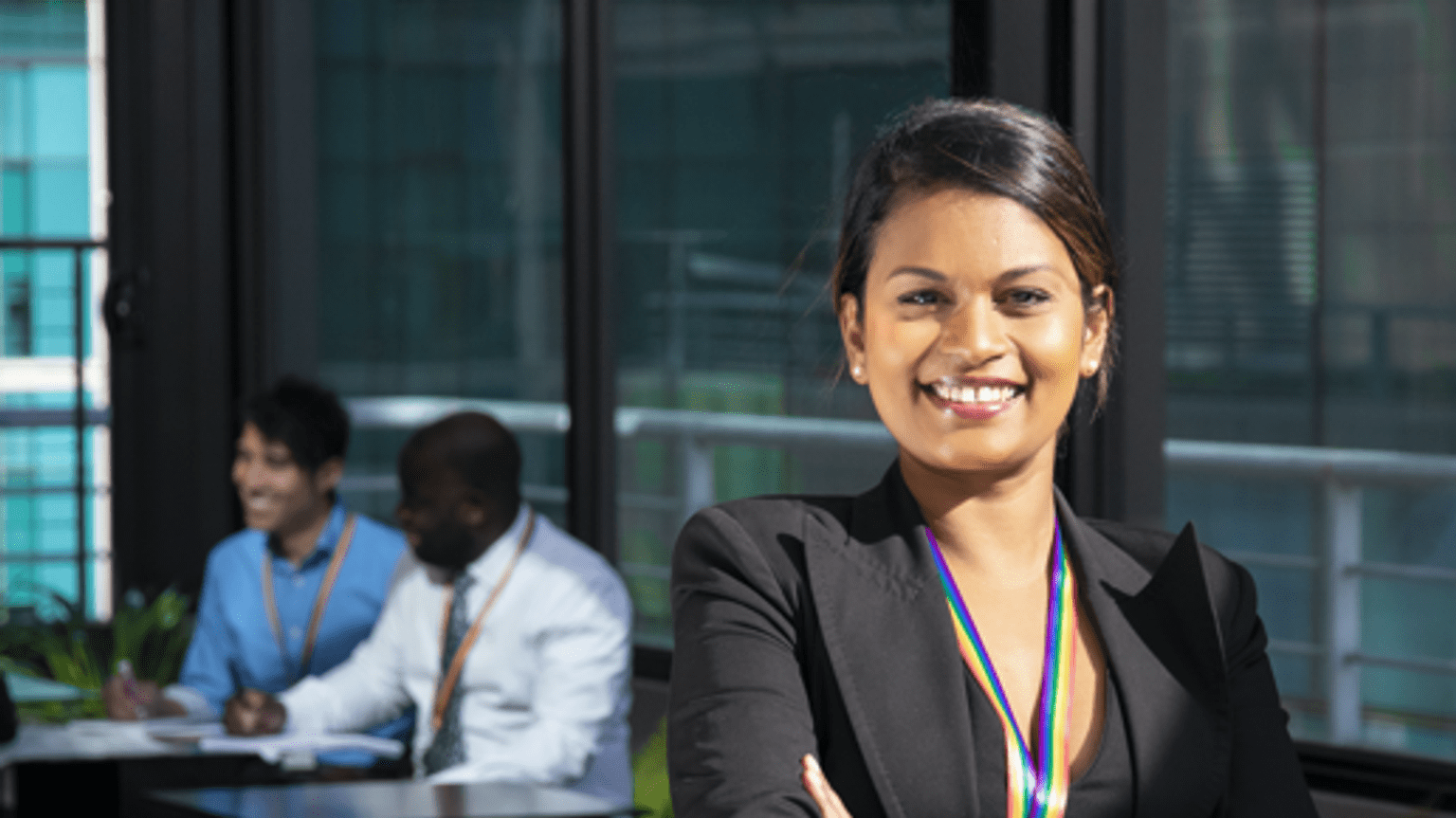 a woman dress in corporate attire has her arms crossed while smiling at the camera