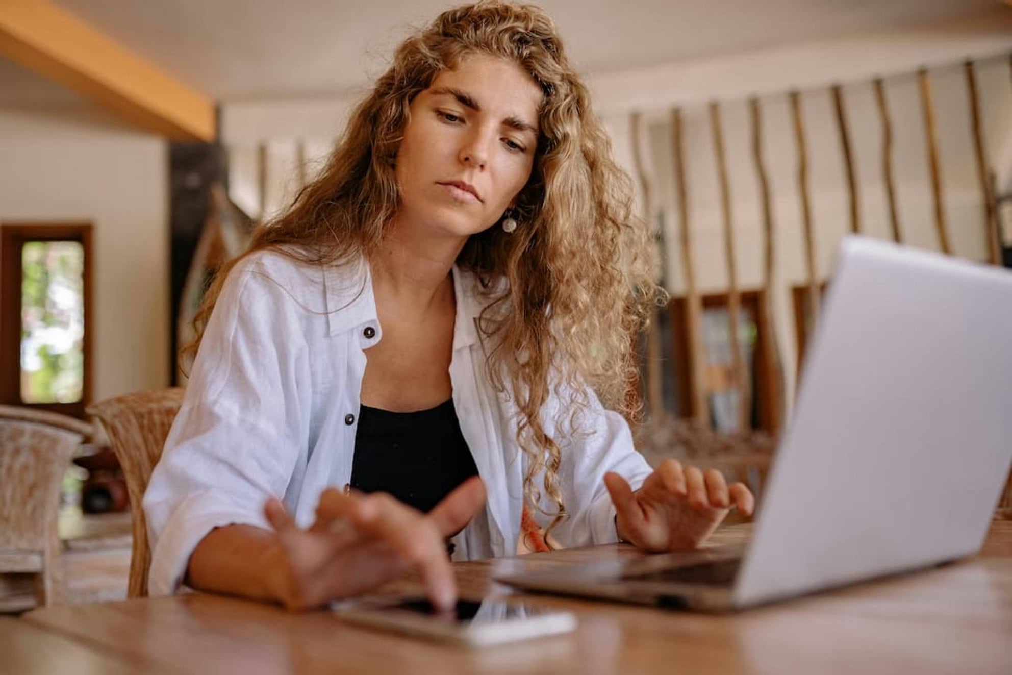 Woman sitting at table with laptop and mobile phone