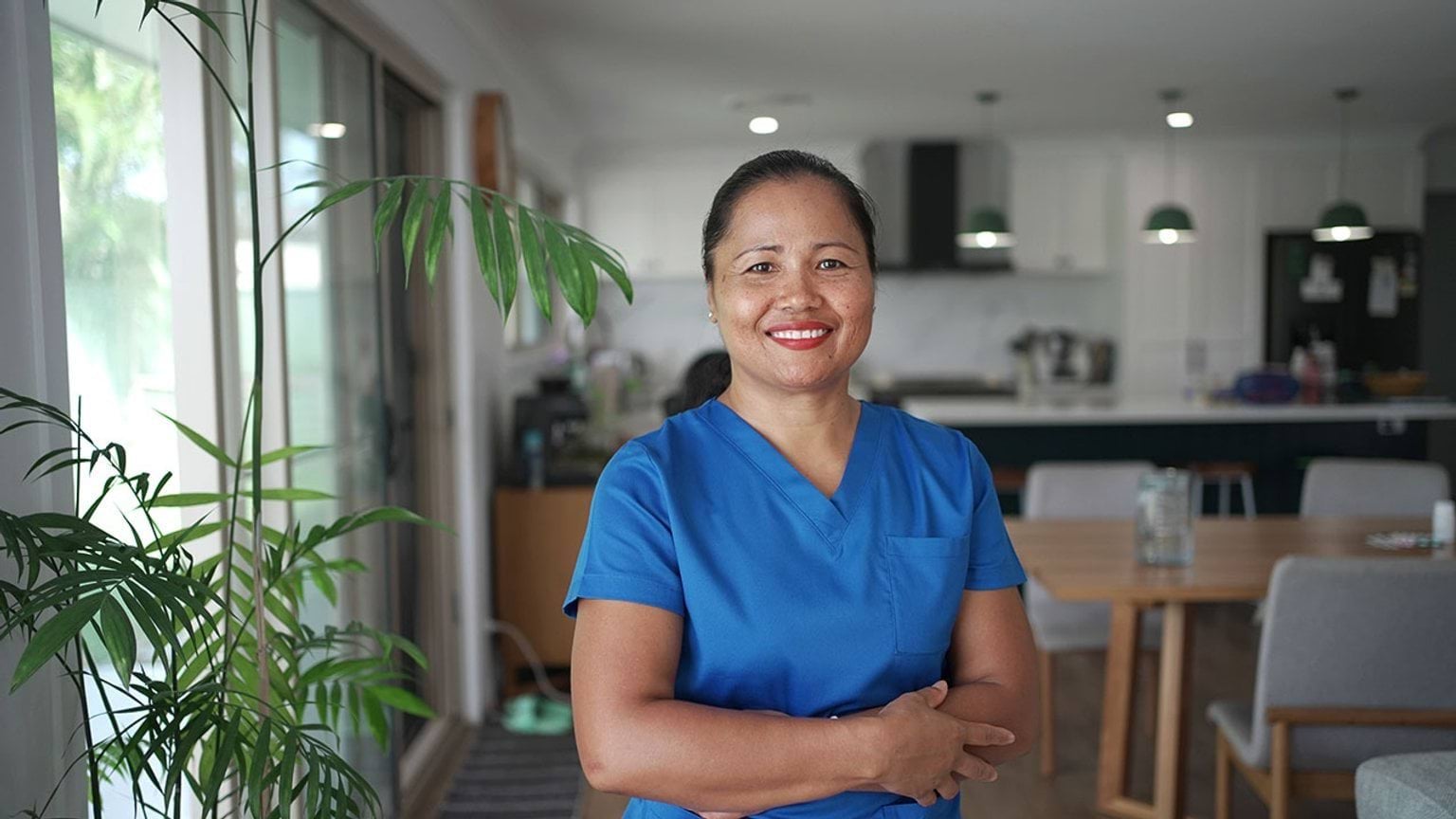Personal care worker in home or aged care centre setting, they are smiling into the camera.