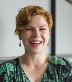 A photo of Leisl Egan smiling. She has short blond hair and is wearing a black top with green leaves.