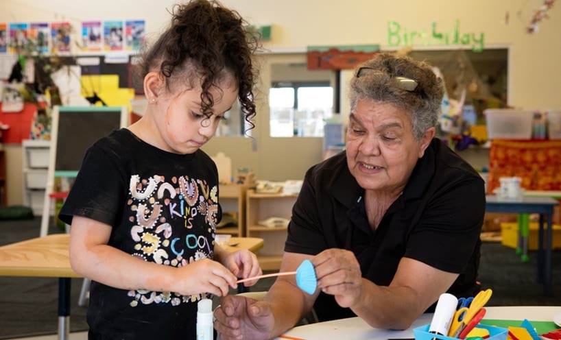 An educator helping a child with craft