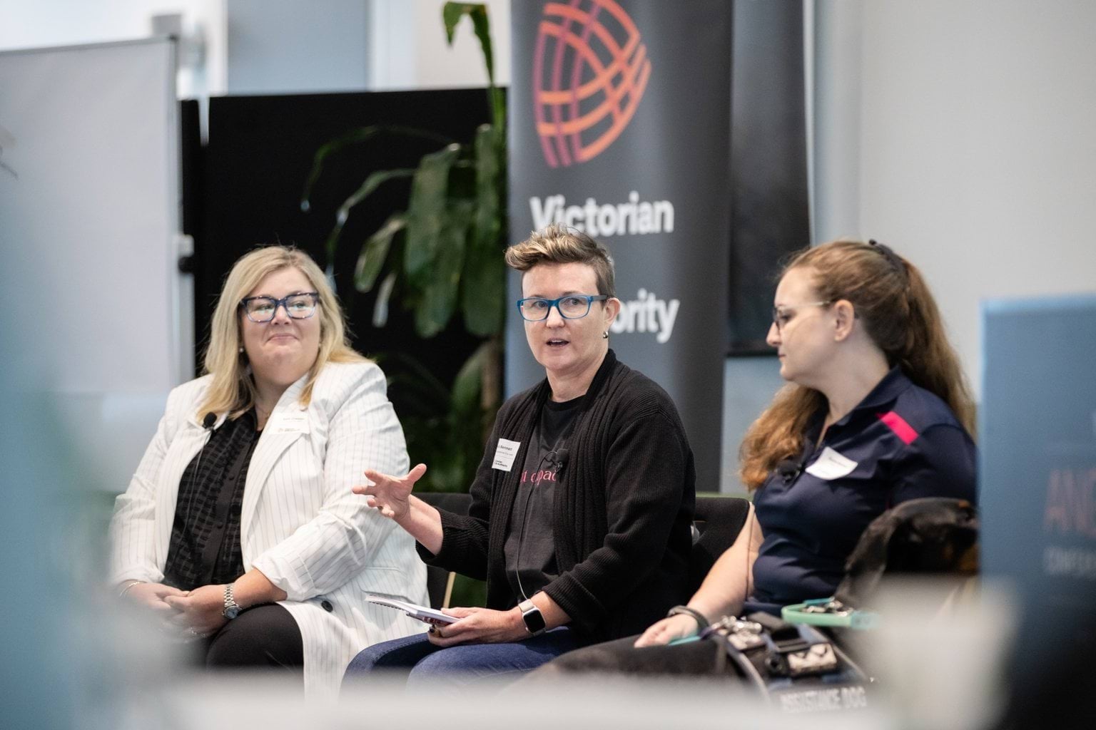 Three people sitting on chairs presenting and speaking to an audience