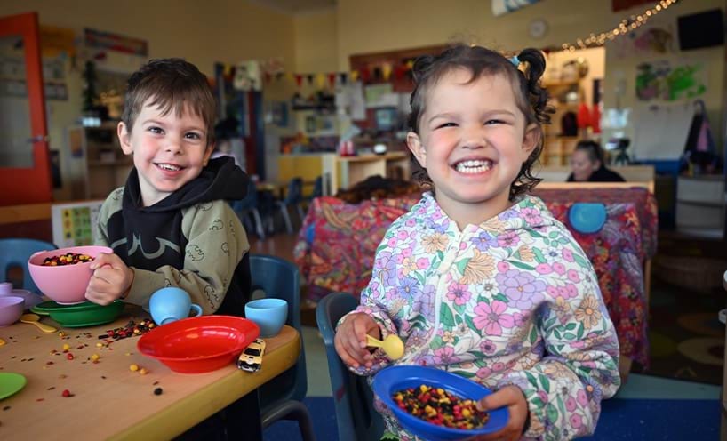 Two children playing with resources and smiling