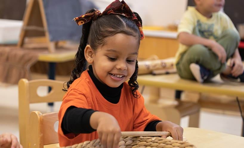 A child sitting with hand picking something from a basket