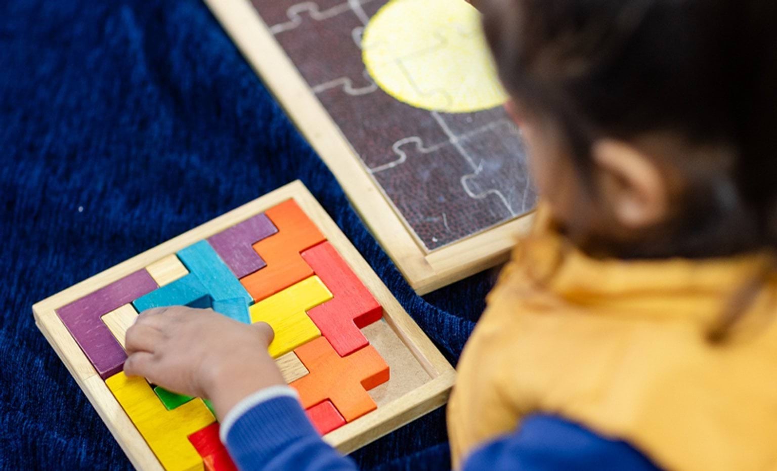 A child solving colorful wooden puzzle on a board