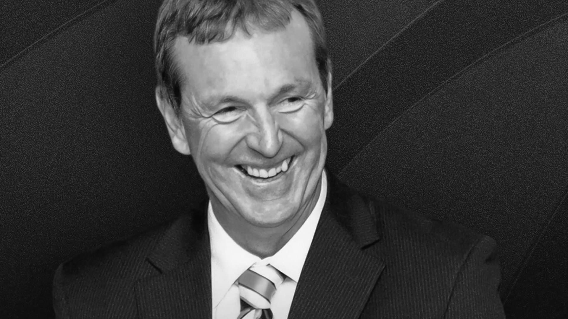 Portrait of Neale Daniher AO smiling and wearing a suit