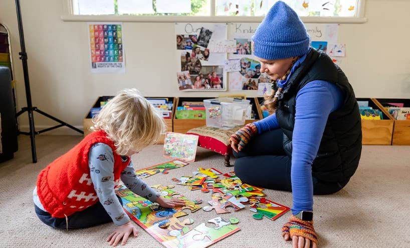 An educator assisting a child who is trying to solve a puzzle