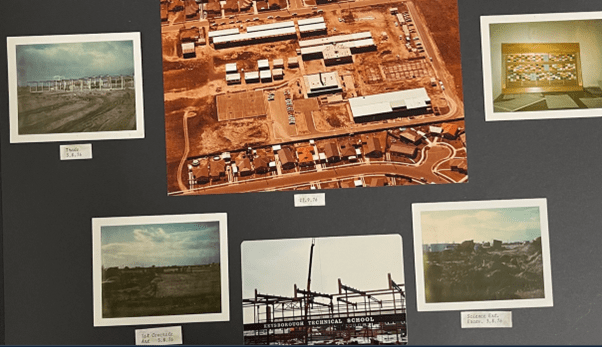 A page from a photo album that shows 5 smaller colour photos that include the school in various stages of construction and one large aerial photo of the entire school grounds.