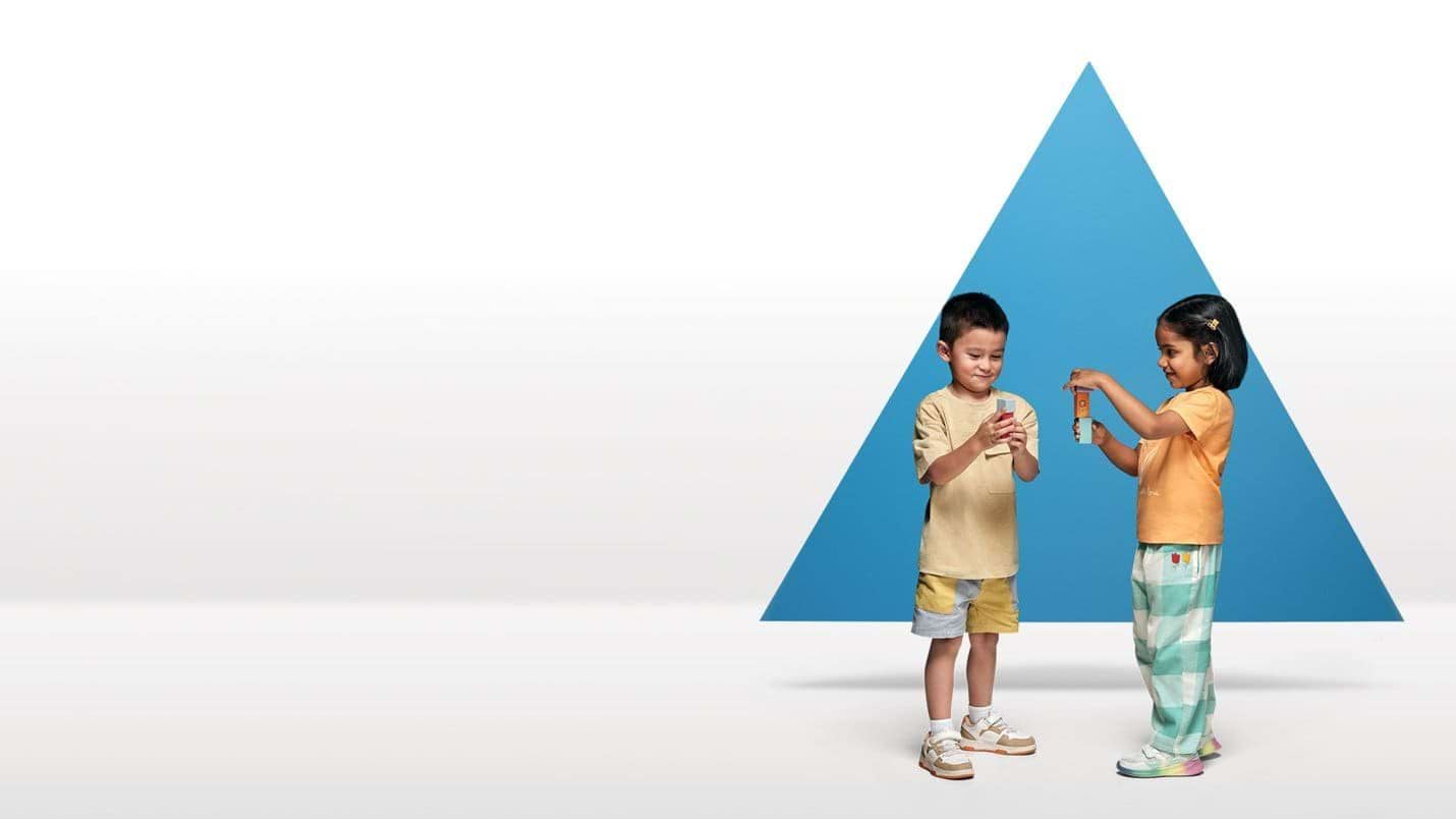 two children play and learn together in front of a blue triangle floating in a white space.