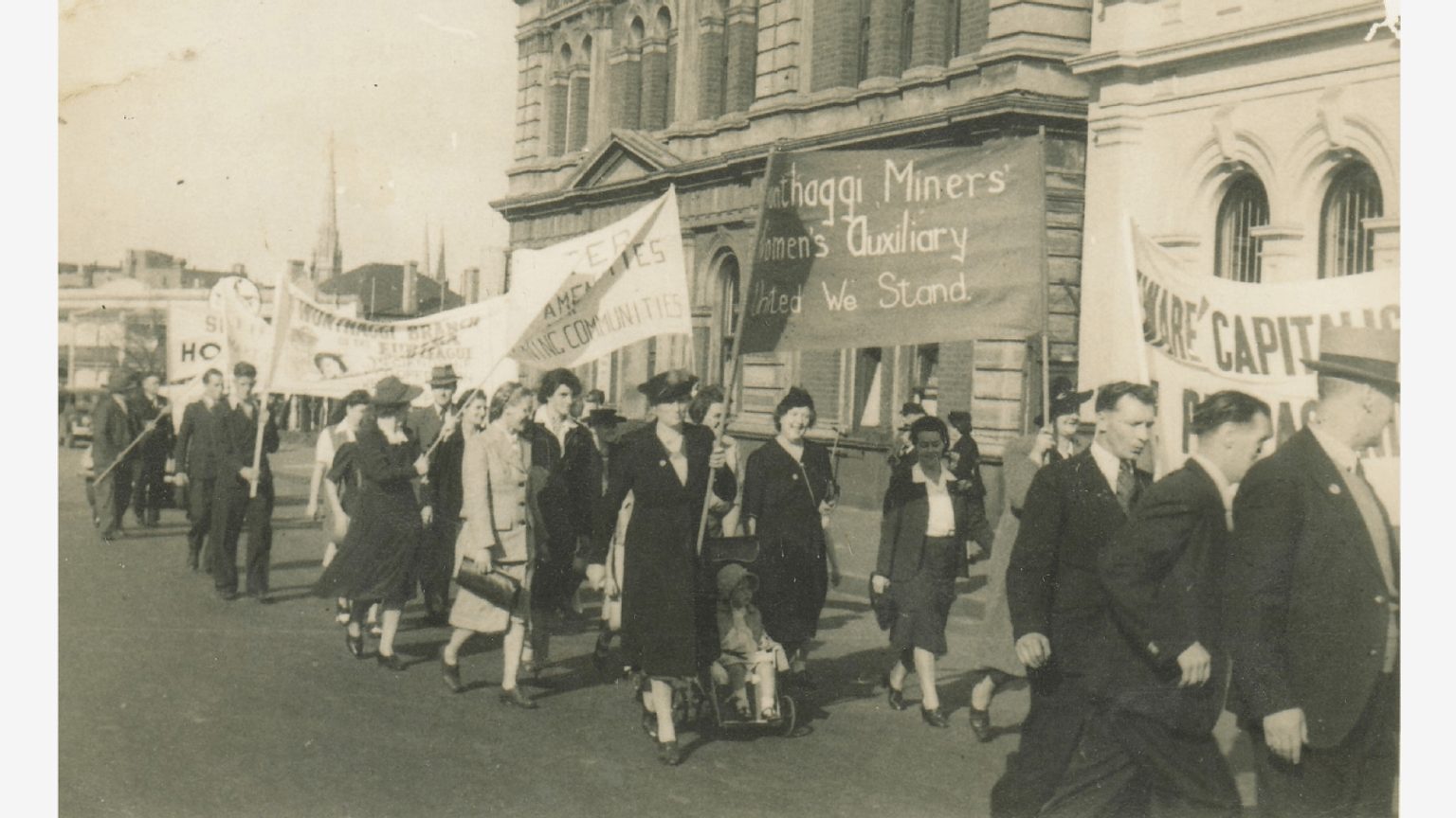 Auxiliary members at the May Day March in Melbourne, late 1940s. Meg Foster holding the WMWA banner, Nancy Stirton beside her and Anne Stirton in the pram.
