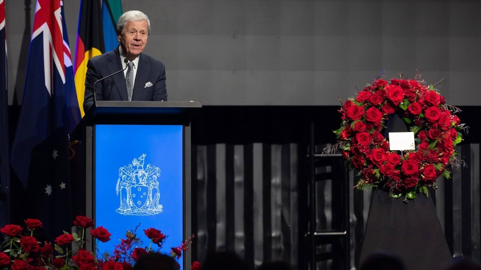 Journalist Ray Martin spoke about Derryn Hinch's life at his State Funeral Service. A wreath is seen next to him on stage