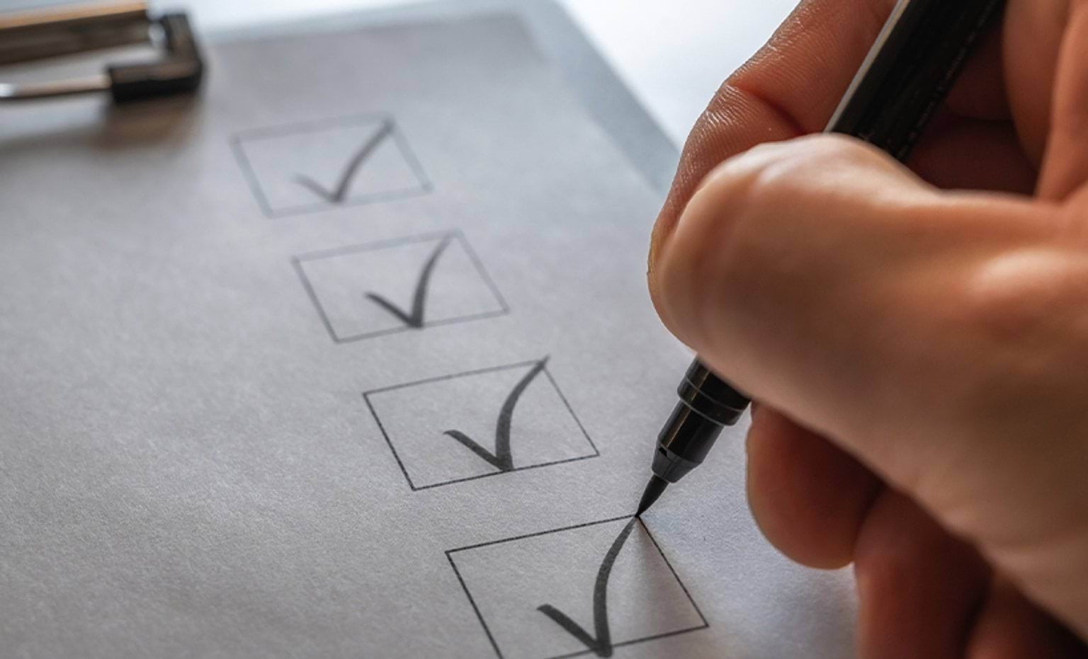 A checklist on a clipboard being ticked off
