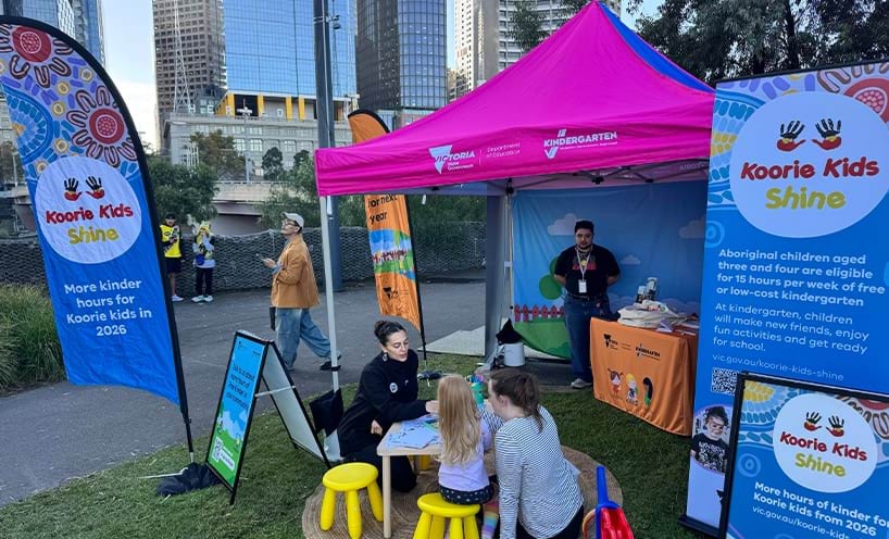 Koorie Kids Shine counter in an outdoor event with a program representative interacting with a parent with child