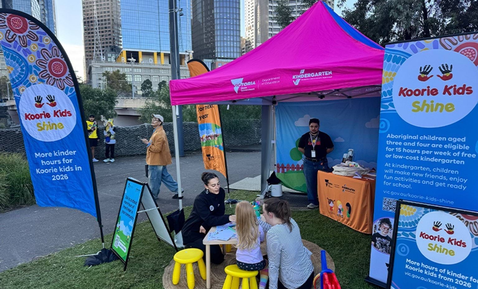 Koorie Kids Shine counter in an outdoor event with a program representative interacting with a parent with child