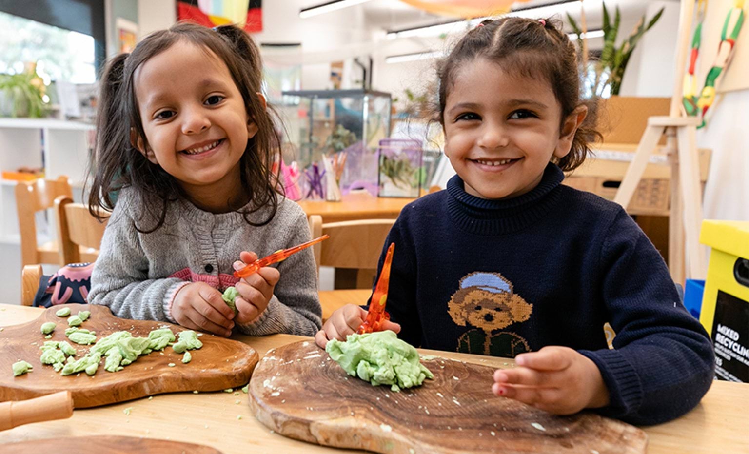 Two children playing with play dough and smiling